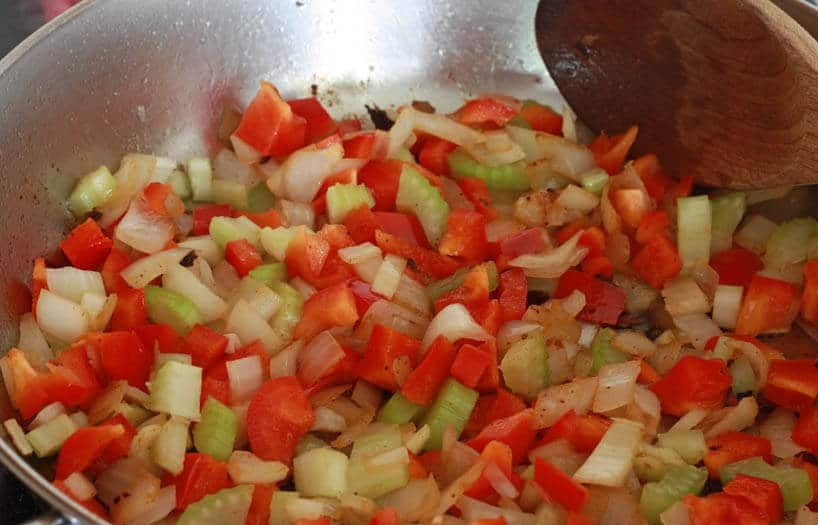 1. Этап. Вкусная говяжья подлива: 6. Нарежьте кубиками томаты, а сельдерей небольшими кусочками. Выложите овощи в сковороду к луку и чесноку.