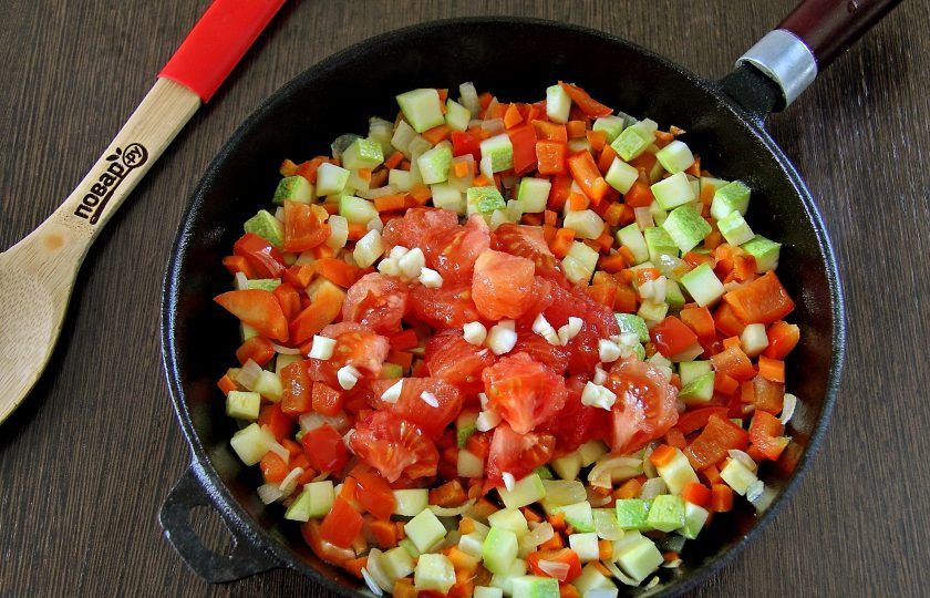 1. Этап. Летний овощной суп: Помидор обдайте кипятком, снимите шкурку и нарежьте кубиками. Добавьте мякоть к обжаренным овощам. Добавьте измельченный ножом чеснок и обжарьте все вместе еще пару минут.