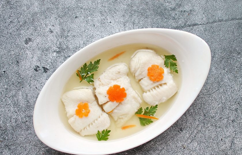 1. Этап. Заливное из палтуса: В форму, в которой будете делать заливное, влейте немного бульона. Выложите сверху кусочки палтуса. Залейте рыбу бульоном, чтобы он только чуточку ее покрывал. Украсьте заливное зеленью и морковью, уберите в холодильник до застывания, примерно на 30-40 минут.