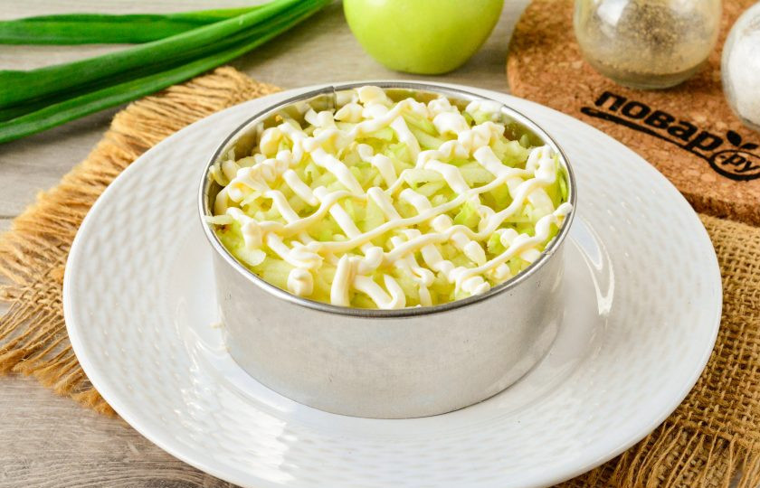 1. Этап. Салат Сказка с черносливом: Кислые зеленые яблоки натрите на крупной терке и распределите в салате четвертым слоем. Яблоки полейте небольшим слоем майонеза.