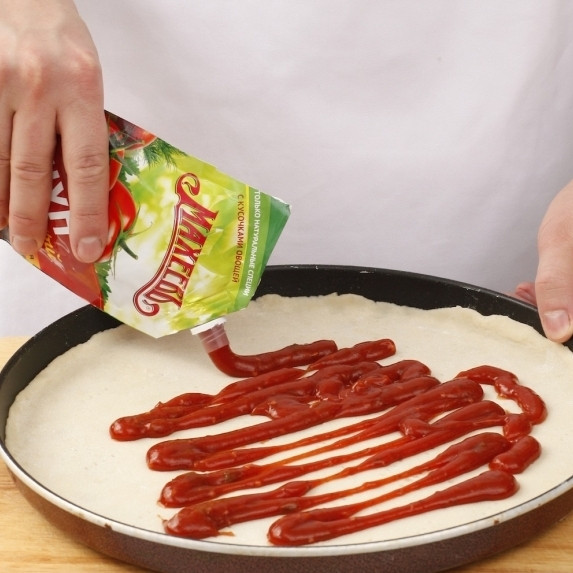 1. Этап. Пицца тонкая: Кладем тесто на рабочую поверхность, присыпанную мукой, и еще раз вымешиваем тесто. Раскатываем его в лепешку, причем диаметр лепешки должен быть существенно больше, чем форма для запекания пиццы (это важно!). Теперь нужно быстро переложить раскатанную лепешку в форму для запекания, и когда тесто начнет постепенно сжиматься, края лепешки нужно закрепить, прижав пальцами к бортикам.