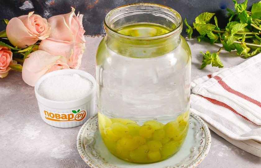 1. Этап. Компот из белого винограда на зиму: Всыпьте ягоды в чистую литровую банку. Вскипятите воду и залейте кипяток в емкость. Накройте крышкой и оставьте пропариваться примерно 5 минут.