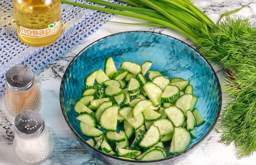 1. Этап. Салат с яйцом, огурцом, зелёным луком и сыром: Нарежьте огурцы полукольцами и высыпьте нарезку в глубокую емкость.