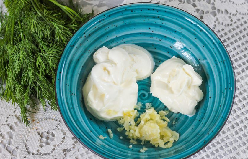 1. Этап. Соус для шаурмы как в ларьках: Выложите охлажденную сметану и майонез в глубокую миску или салатник. Очистите чесночные зубчики и промойте, спрессуйте в емкость. По желанию свежий чеснок можно заменить сушеным гранулированным.