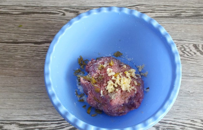 1. Этап. Мексиканские бургеры: Выложите фарш в чашу, добавьте 1 мелко резанный острый перец, 2 зубчика чеснока, соль, черный перец. Хорошо вымешайте. Отбейте фарш несколько раз о дно чаши.