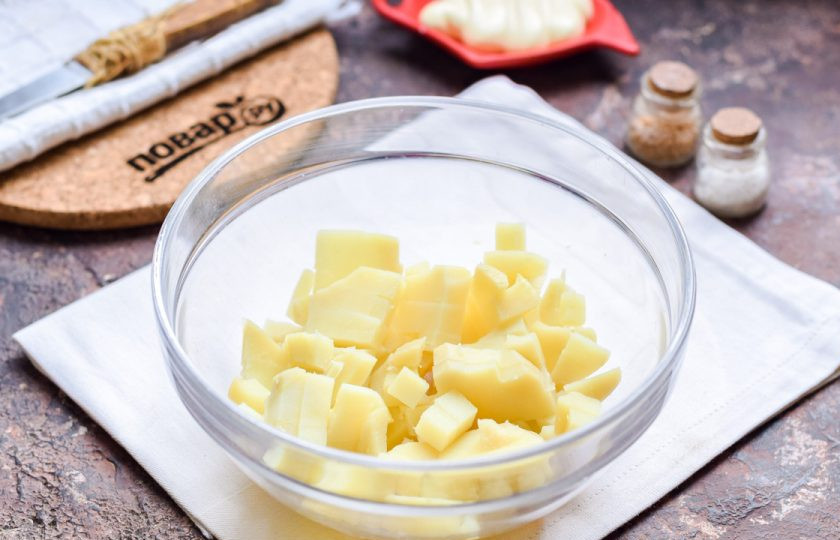 1. Этап. Мясной салат на Новый год: Картофель очистите и нарежьте небольшими кубиками, переложите в салатник.