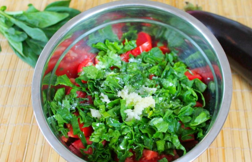 1. Этап. Салат из печеных баклажанов с помидорами: Заправляем салат оливковым маслом, затем добавляем соль и пропущенный через пресс чеснок. Перемешиваем.