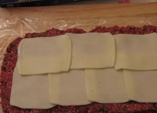 1. Этап. Мясной рулет с сыром: 4. Поверхность мяса накрыть тонко нарезанными ломтиками сыра. Использовать можно плавленый бутербродный сыр, твердый или моцареллу, например.