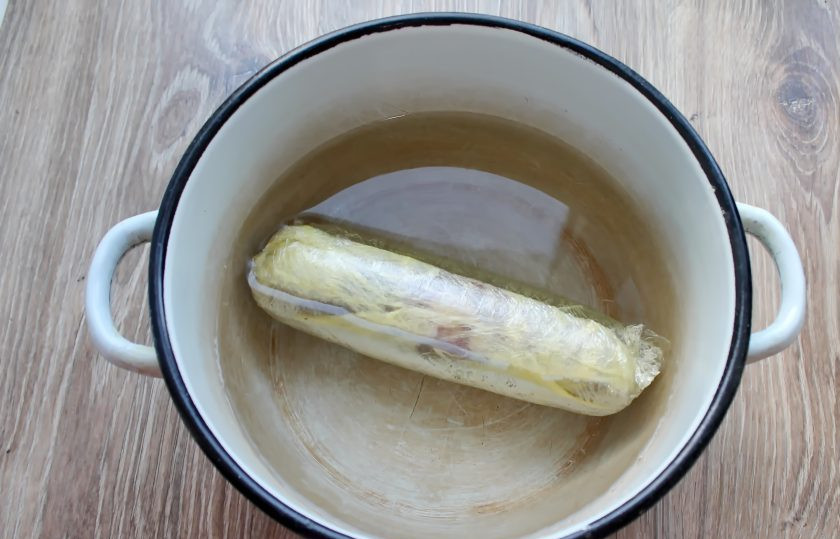 1. Этап. Сальчичон из курицы: В кастрюлю налейте холодную воду и выложите завернутый сальчичон. Поставьте на средний огонь и доведите до кипения. Варите в течение 40 минут при медленном кипении. Оставьте в воде до остывания.