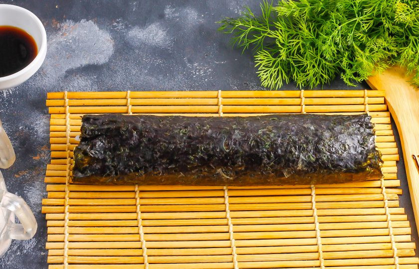 1. Этап. Спайси роллы: Аккуратно сверните нори с начинкой, используя коврик. Незаполненную часть нори смажьте водой и докрутите ролл до конца.