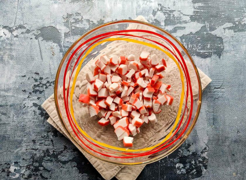 1. Этап. Крабовый салат с грецкими орехами: Крабовые палочки мелко нарежьте и выложите в тарелку.