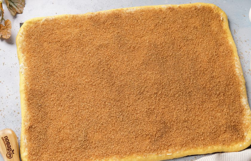 1. Этап. Тыквенные синнабоны: Раскатайте тесто в прямоугольник, толщиной не более 7 мм. Смажьте всю поверхность мягким сливочным маслом, посыпьте тростниковым сахаром, смешанным с корицей.