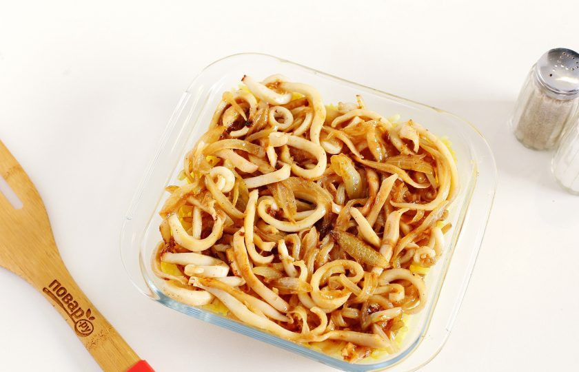 1. Этап. Кальмары по-гречески: Форму для запекания смажьте маслом. Выложите отваренный ранее рис, а на него выложите лук и кальмары.