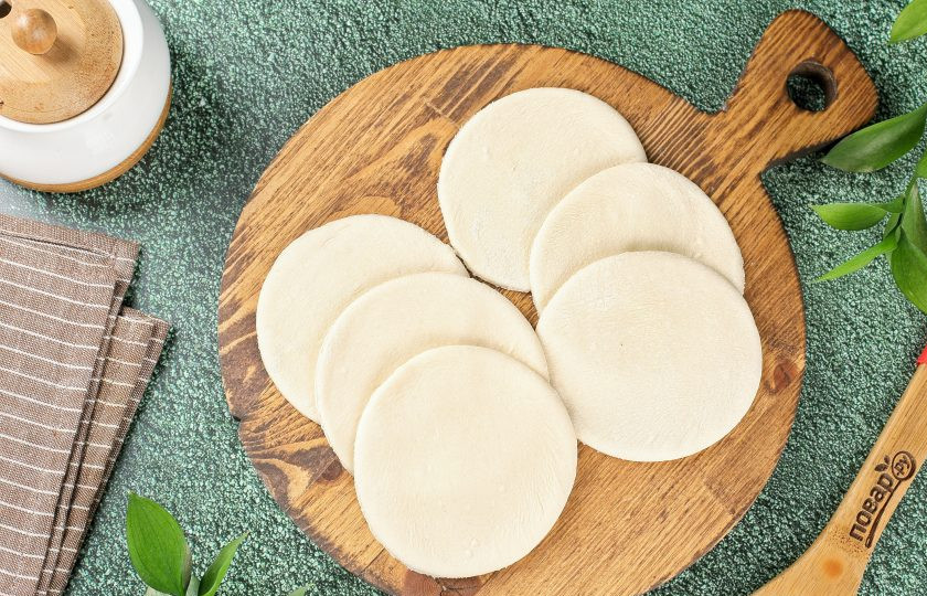 1. Этап. Пирожные Лотосы с творогом и сухофруктами: Тесто раскатайте в тонкий пласт и нарежьте кружочками диаметром около 8-10 см.