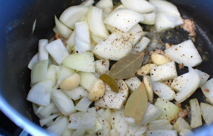 1. Этап. Каччиаторе (курица по-итальянски): 6. Выложите луковицу и целые очищенные зубчики чеснока, посолите и поперчите, добавьте лавровый лист. Обжаривайте овощи несколько минут.