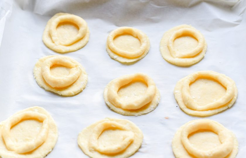 1. Этап. Творожное печенье с апельсином: Теперь оторвите немного теста, раскатайте, после вырежьте круглые заготовки. Также из теста скатайте тонкие длинные жгуты, выложите их на каждую круглую заготовку.