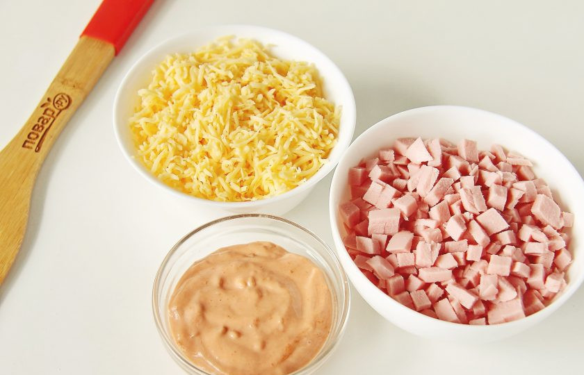 1. Этап. Мини пицца: Пока тесто поднимается, подготовьте начинку. Для соуса соедините кетчуп и майонез. Колбасу нарежьте мелкими кубиками. Сыр натрите на мелкой терке.