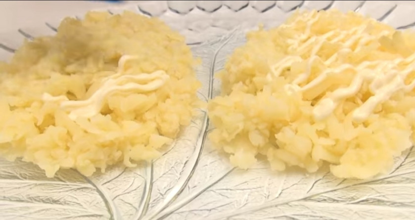 1. Этап. Салат Еловые шишки: 2. Картофель разделяем на 2 части, в блюдо выкладываем его в форме шишек, сверху слегка поливаем майонезом.