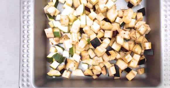 1. Этап. Простой овощной салат: Баклажан и цуккини вымойте и порежьте некрупными кусочками. Выложите в форму для запекания.