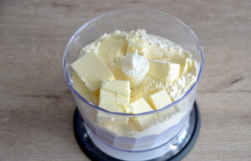 1. Этап. Пирожное Корзиночка с масляным кремом: В чашу миксера выложите муку, разрыхлитель, соль, сахарную пудру (70 грамм), нарезанное кубиком холодное сливочное масло (90 грамм). Пробейте все до мелкой крошки.