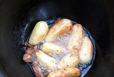 1. Этап. Утка, тушенная с картошкой в казане: Жира у нас натопилось много, выкладываем в него картофель для обжарки. Если у вас небольшие картофелины, их можно не разрезать, а большие разрежьте на крупные куски. Обжариваем картофель до румяной корочки. Огонь под казаном довольно большой.