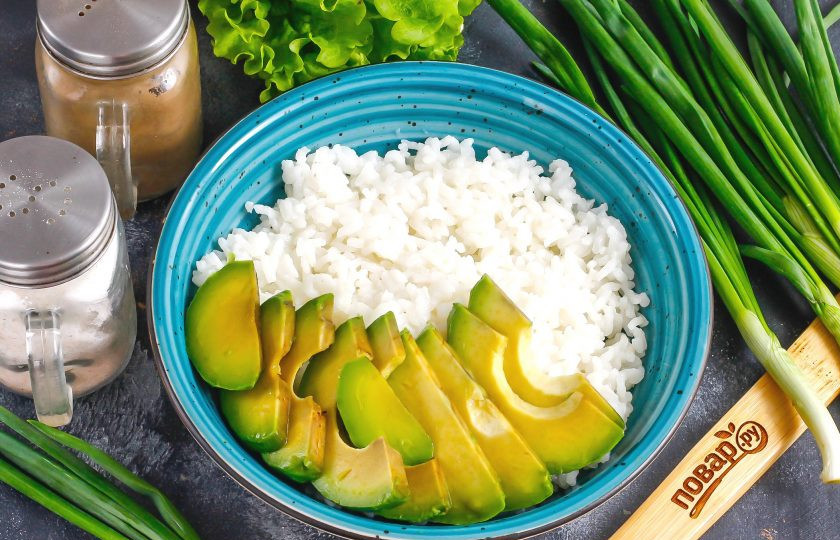 1. Этап. Боул с лососем и авокадо: Половину авокадо очистите от кожуры, нарежьте ломтиками. Выложите в чашу отварной рис и разровняйте. На одну половину выложите нарезку авокадо. По желанию сбрызните ее лимонным соком, чтобы она не потемнела или уксусом.