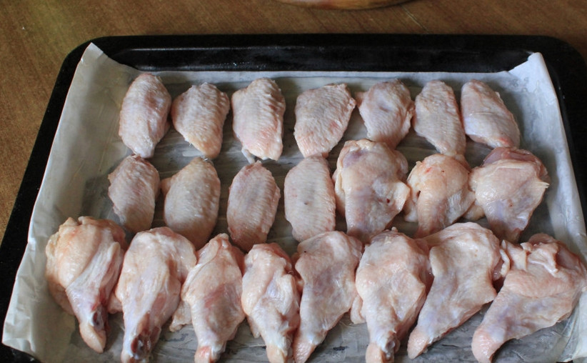 1. Этап. Куриные крылышки Баффало: Застилаем противень бумагой для выпечки. Смазываем бумагу сливочным маслом, выкладываем на нее крылышки. Отправляем их в духовку на 30 минут, температура — 200 градусов.