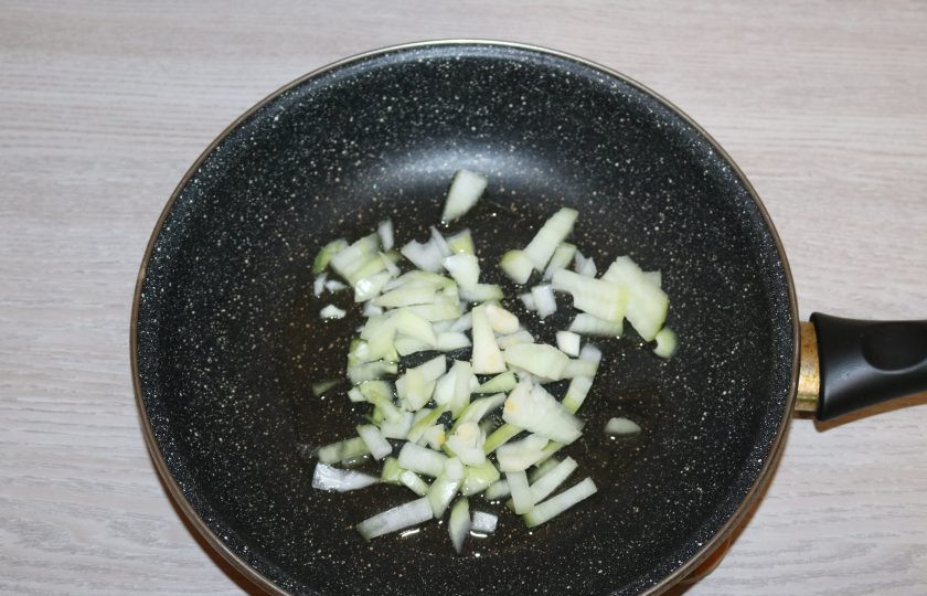 1. Этап. Фасоль по-сербски: Лук обжарьте в небольшом количестве масла до прозрачного цвета.