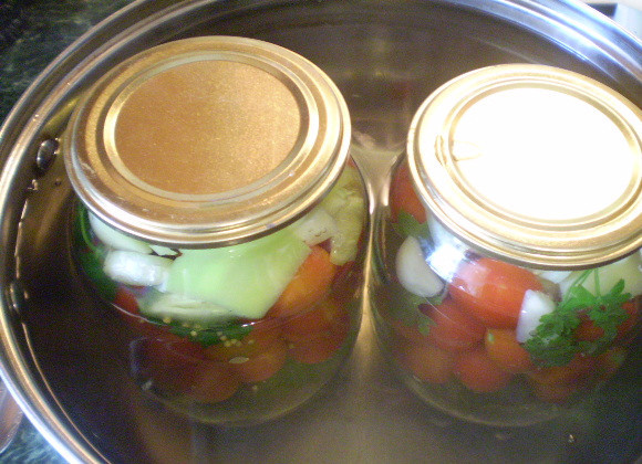 1. Этап. Закатка овощного ассорти: Заливаем кипятком овощи и стерилизуем банки по 5 минут с момента закипания воды в кастрюле. Потом вливаем уксус и закатываем банки.