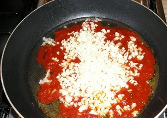 1. Этап. Суп из говядины с томатной пастой: Мелко рубим очищенные дольки чеснока. Обжариваем их вместе с томатной пастой на сковороде, смазанной маслом.