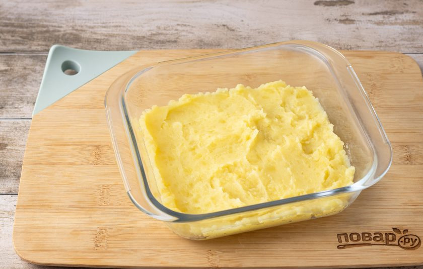 1. Этап. Картофельная запеканка с сосисками и грибами: Выложите половину картофельного пюре в форму для запекания.