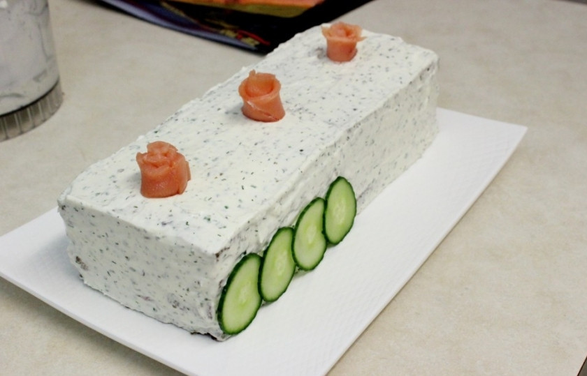 1. Этап. Торт с копченым лососем: Выложите кусочки огурца у основания торта. Также можете его украсить, сформировав розочки из кусочков лосося, как это показано на фото.