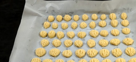 1. Этап. Печенье Орешки: Разделите каждый шарик теста на две части. Выложите половинки шариков на противень. Прижмите уголки с двух сторон половинок, чтобы создать форму. С помощью шпажки сделайте продольный и боковые надрезы, имитируя кору ореха.