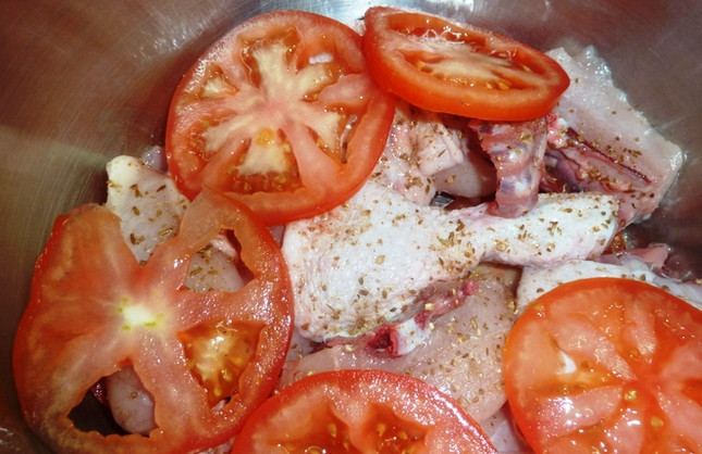 1. Этап. Курица, тушенная в казане: Нарежьте помидоры колечками. Складывайте томаты и куски курицы слоями в казане. Перед этим натрите птицу солью и смесью пряностей. Можно взять уже готовую приправу, а можно истолочь специи в ступке самостоятельно. Оставьте курицу мариноваться в холодильнике на два-три часа.