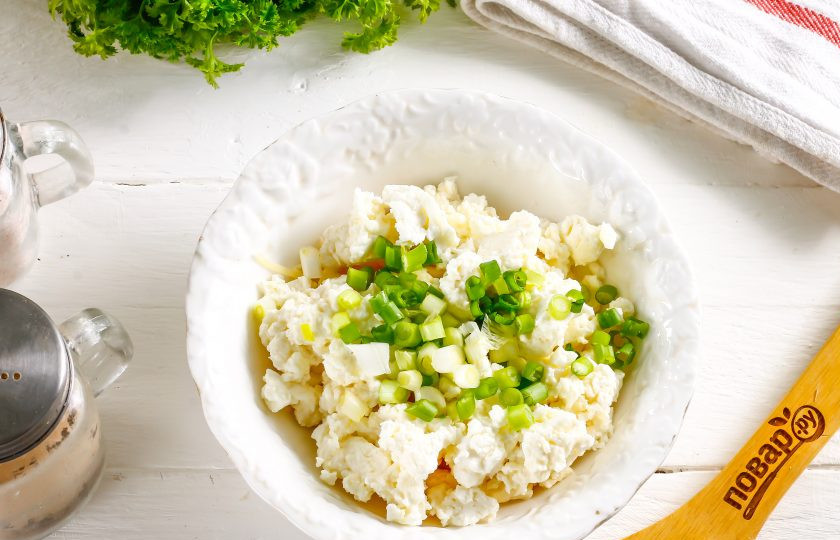 1. Этап. Рулет на год Крысы: Промойте зеленый лук и измельчите его, всыпьте в емкость к творогу, добавив немного соли. Тщательно все перемешайте, добавив майонез любой жирности.