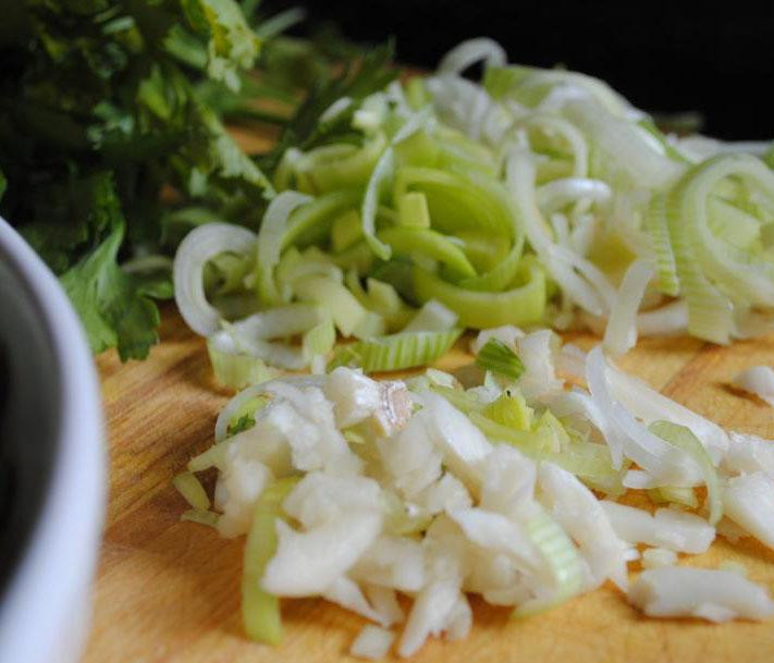 1. Этап. Итальянский суп с кальмарами: 2. Приготовить овощи. Лук порезать полукольцами. 2 зубчика чеснока нарезать на тонкие пластины, а остальной чеснок мелко порубить. Петрушку мелко нашинковать. Стебель лука-порея нарезать на колечки.