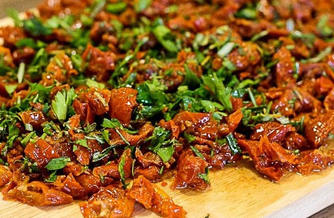 1. Этап. Свинина в тесте в духовке: Нарезаем вяленые помидоры, смешиваем их с измельченной зеленью.