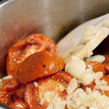 1. Этап. Суп с запеченным чесноком, помидорами и сыром: 5. В большой кастрюле на среднем огне нагреть оставшиеся 2 столовые ложки оливкового масла. Добавить мелко нарезанный репчатый лук и 2 дольки измельченного чеснока. Жарить до появления аромата, пока лук не станет прозрачным. Затем добавить запеченные помидоры (с их соком из противня) и запеченный чеснок.