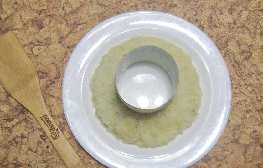 1. Этап. Салат Гранатовый браслет с языком: Картофель сварите, охладите и натрите на терке. В центр большой тарелки поставьте салатное кольцо или обычный стакан. Выложите вокруг него первый слой салата из картофеля.