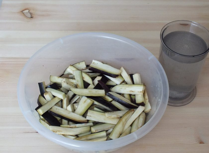 1. Этап. Острый салат на зиму: В 1,5 литрах воды растворите 3,5 ст.л. соли. Баклажаны выложите в чашу и залейте соленым раствором.