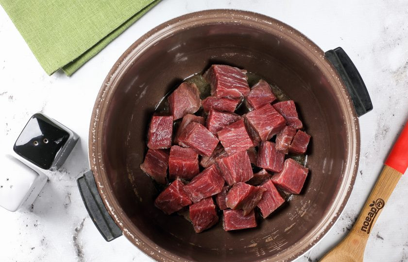 1. Этап. Томлёная говядина в мультиварке: Выложите кусочек масла в чашу мультиварки, растопите и добавьте нарезанное кусочками мясо.