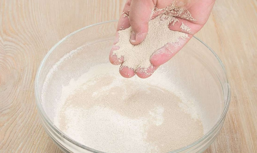 1. Этап. Хлеб с сухофруктами в духовке: Досыпьте сухие дрожжи, перетирая их руками с мукой.