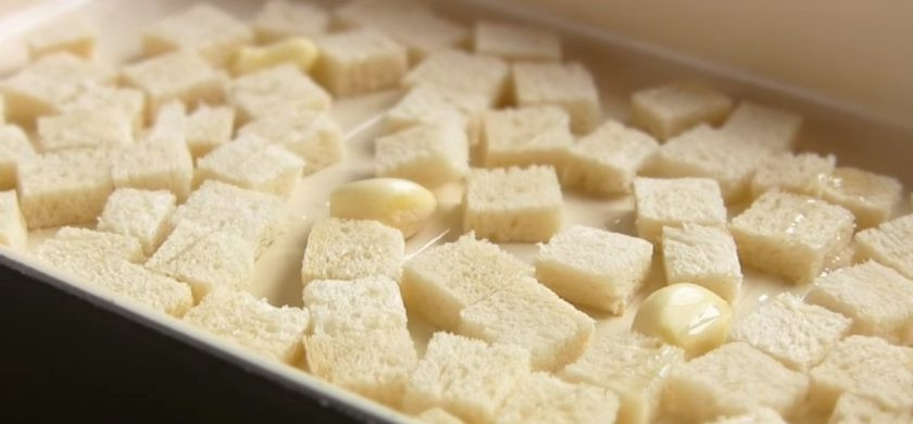 1. Этап. Салат Цезарь с курицей по-домашнему: 2. Выложите филе в миску, накройте крышкой и дайте постоять ему в течение 10 минут. Для сухариков срежьте из хлеба корочки, нарежьте мякиш на кубики небольшого размера и выложите на противень.