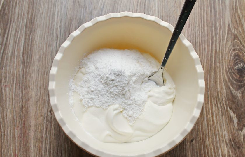 1. Этап. Торт без выпечки из батона: Сметану переложите в миску, добавьте сахарную пудру и перемешайте до однородной массы.