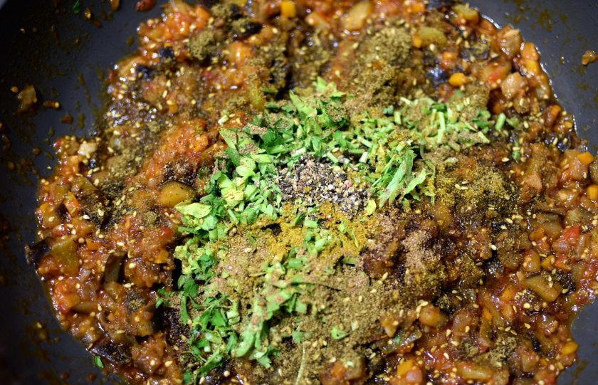 1. Этап. Пряная баклажанная икра: Добавьте молотые специи – карри, гарам масалу, затар и свежетолченую смесь перца горошком. Отправьте в сковороду пару горстей рубленой мелко петрушки – лучше одних листьев. Перемешайте несколько раз и снимите с огня.