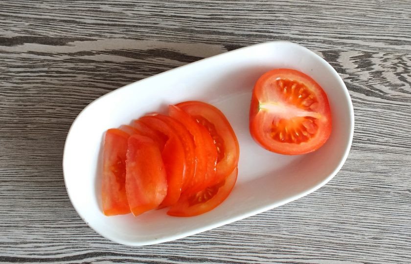 1. Этап. Пикша в духовке под сыром: Помидор нарежьте тонкими ломтиками.