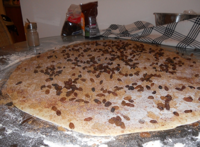 1. Этап. Булочки с корицей и изюмом: Сначала смажьте тесто растопленным сливочным маслом, затем посыпьте корицей и коричневым сахаром, после уложите сверху изюм.