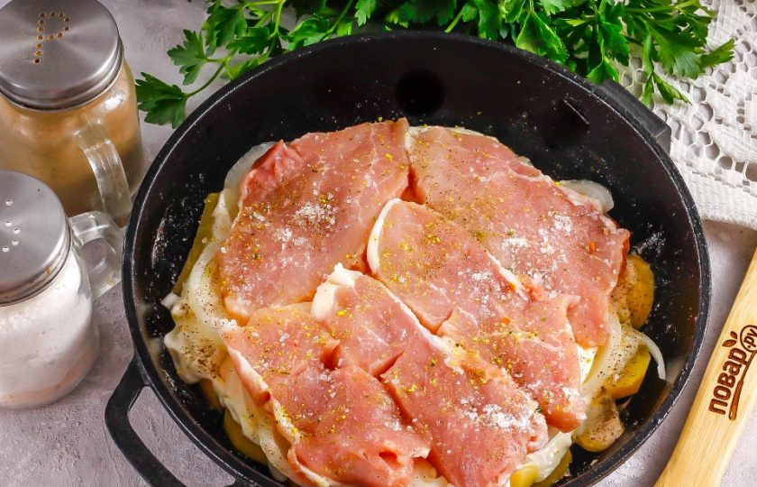 1. Этап. Картошка с мясом в духовке: Мясо нарежьте тонкими широкими ломтиками и выложите на лук. Посолите, поперчите и присыпьте приправой для мяса. Желательно выбирать свинину с небольшой сальной прослойкой, чтобы мясо не получилось суховатым на вкус.