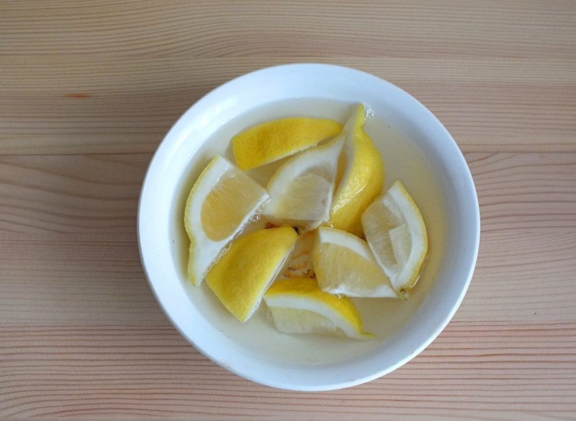 1. Этап. Морковный кекс со сметанно-лимонной пропиткой: Приготовьте пропитку. Половинку лимона разрежьте на кусочки. Залейте кипятком и оставьте на 15 минут, для того чтобы вышла горечь.