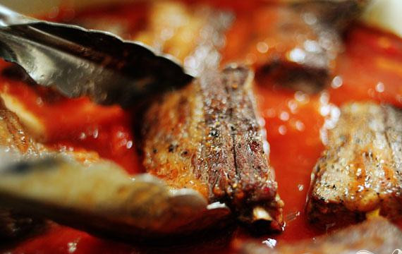 1. Этап. Говяжьи ребрышки в томатном соусе: 2. Слить масло. Добавить чеснок и лук в кастрюлю. Перемешать и готовить 1-2 минуты. Затем добавить помидоры, томатный соус, вино, соль, красный перец, тимьян. Перемешать до однородности. Щипцами выложить ребрышки обратно в кастрюлю, погружая их как можно больше в соус. Накрыть и поместить в духовку. Тушить от 3 1/2 до 4 часов. Ребрышки должны быть нежными. Готовым ребрышкам дать остыть, затем плотно закрыть и поставить в холодильник. Дать кастрюле с соусом остыть немного, затем поместить в холодильник на несколько часов или на ночь.